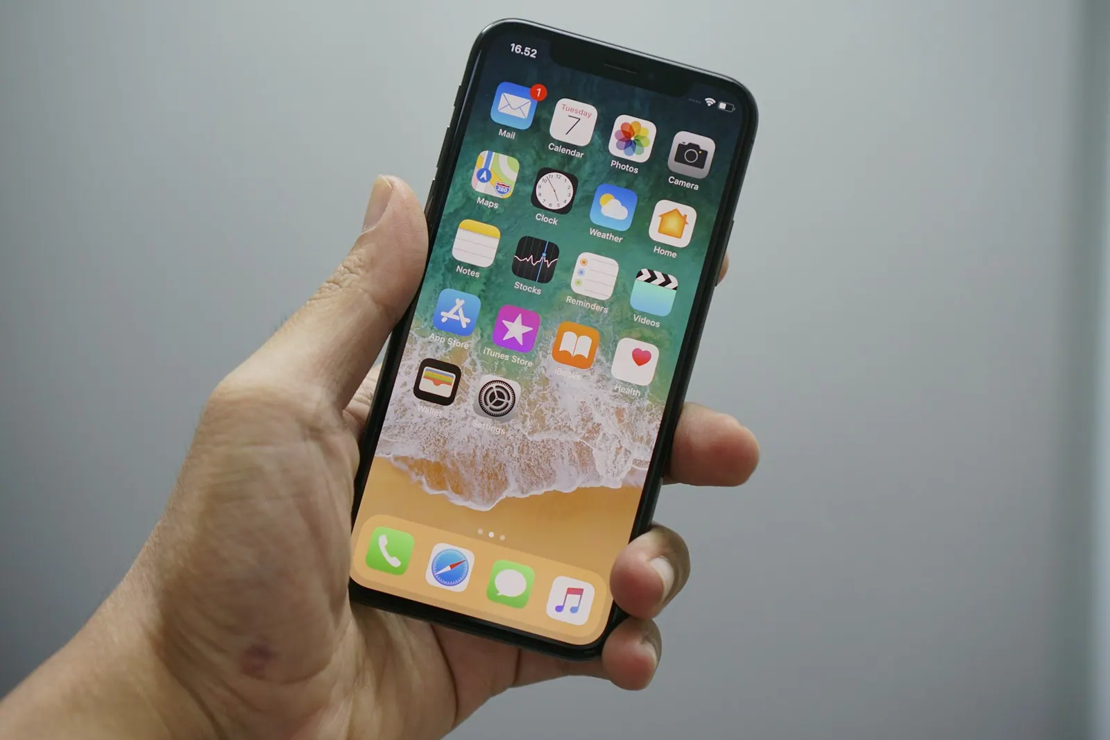 iPhone en la mano con Apple Wallet listo en la pantalla de inicio