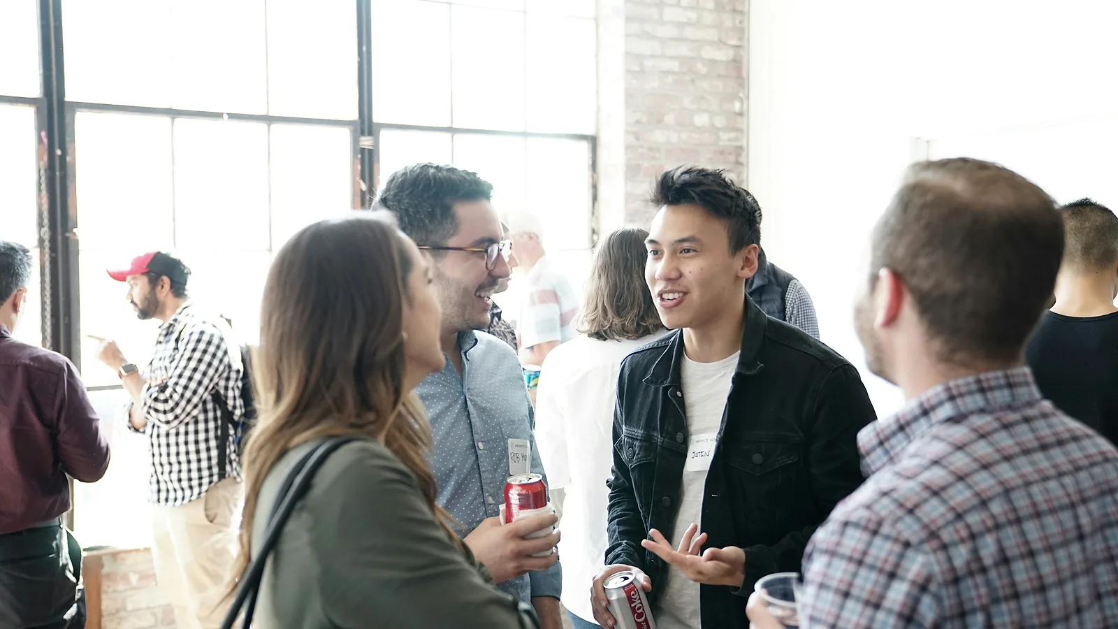 Persone che parlano a un evento di networking con i badge al collo, il momento in cui ci si scambia i contatti